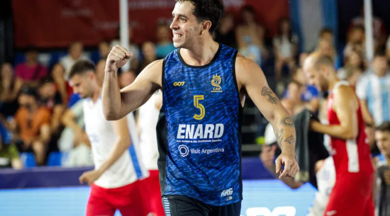A basketball player in a blue jersey with the number 5 celebrates with a raised fist on the court.
